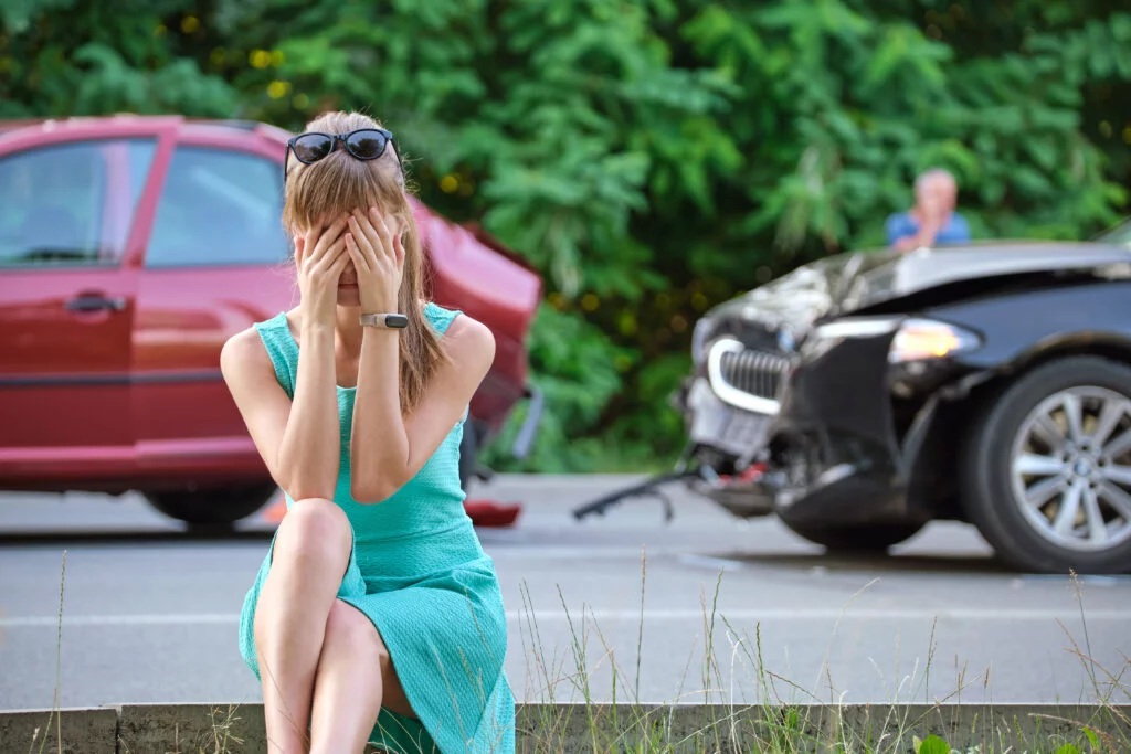 A driver on the phone beside her damaged car after a crash