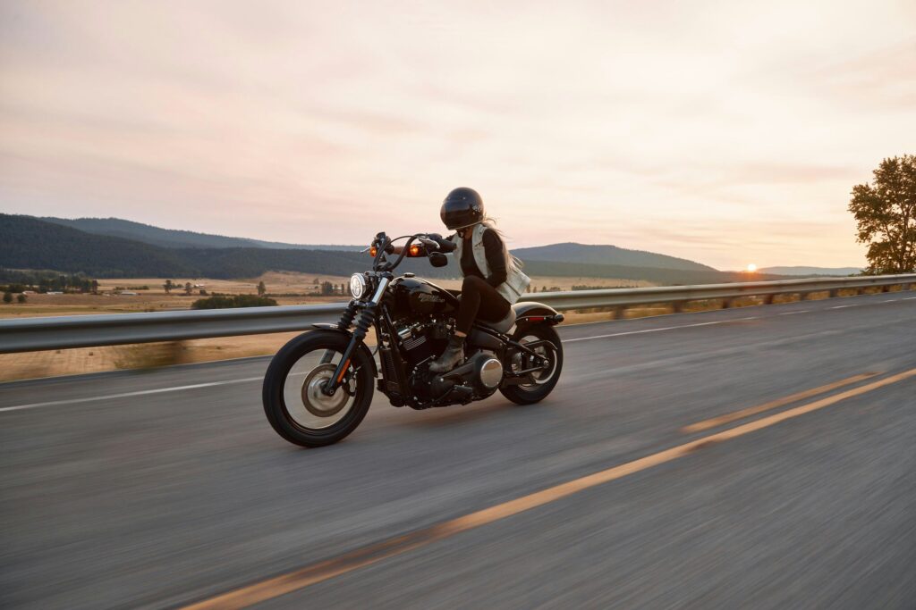A motorcyclist riding on an open road at sunset