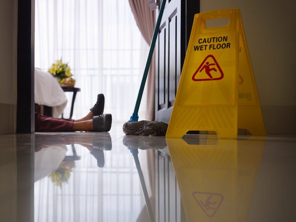 A worker who slipped on a wet floor next to a caution sign